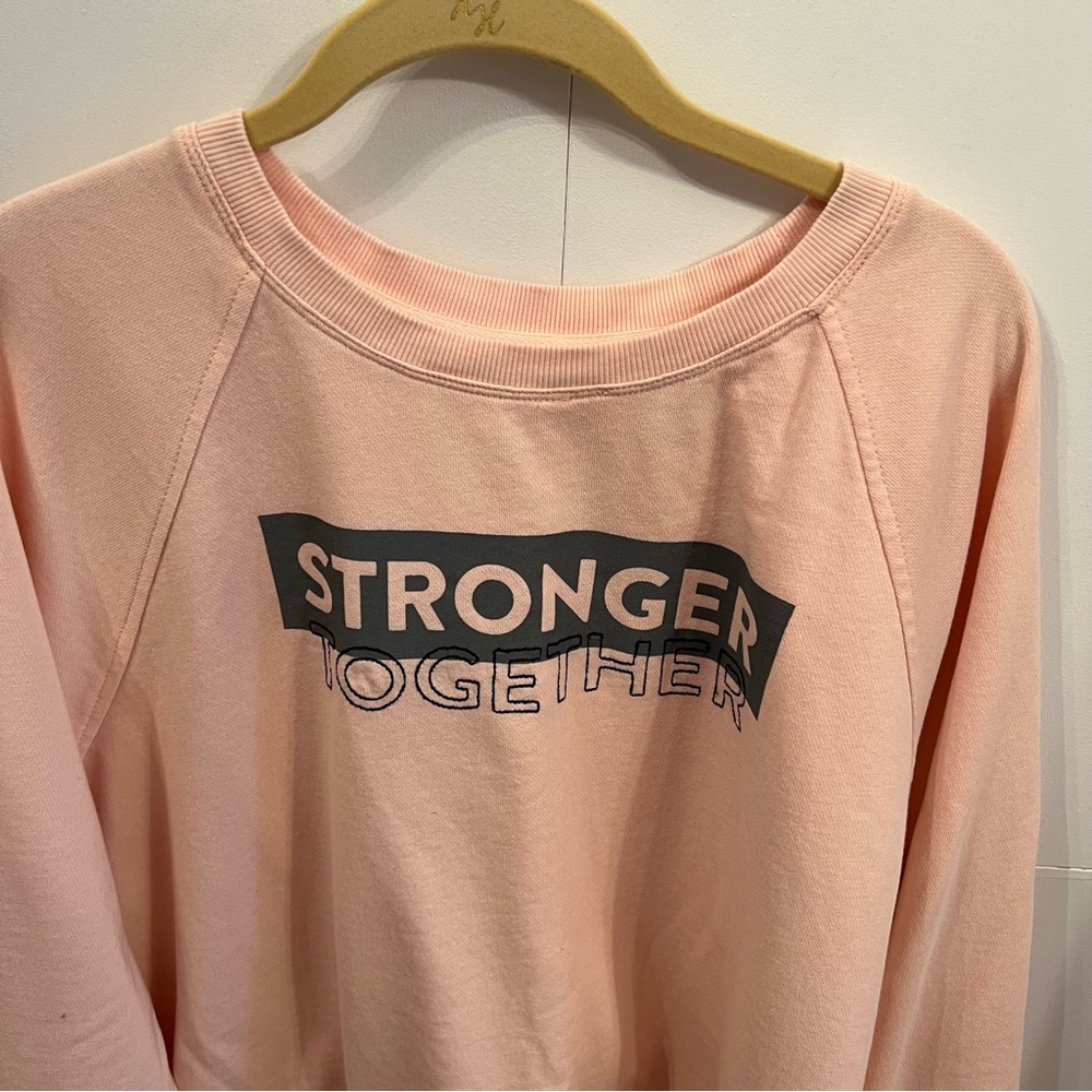 Peloton  light weight sweatshirt. Color is between a peach/light orange.